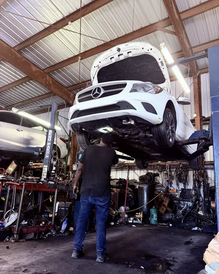 A technician under a raised car in the Front Line Auto bay