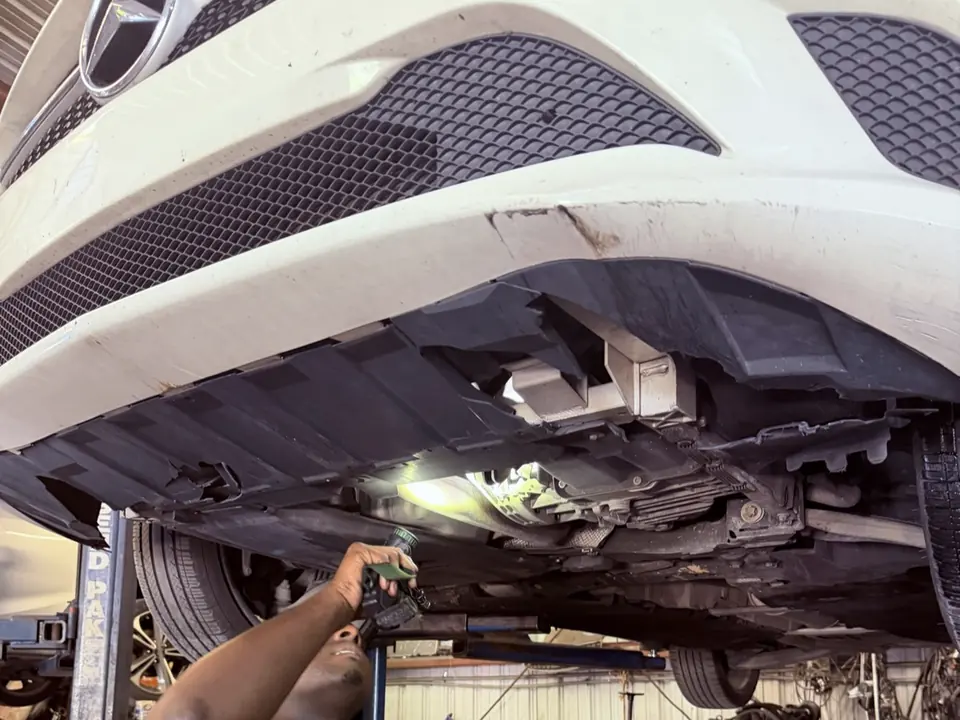 A technician inspecting the underbody of a car on the lift