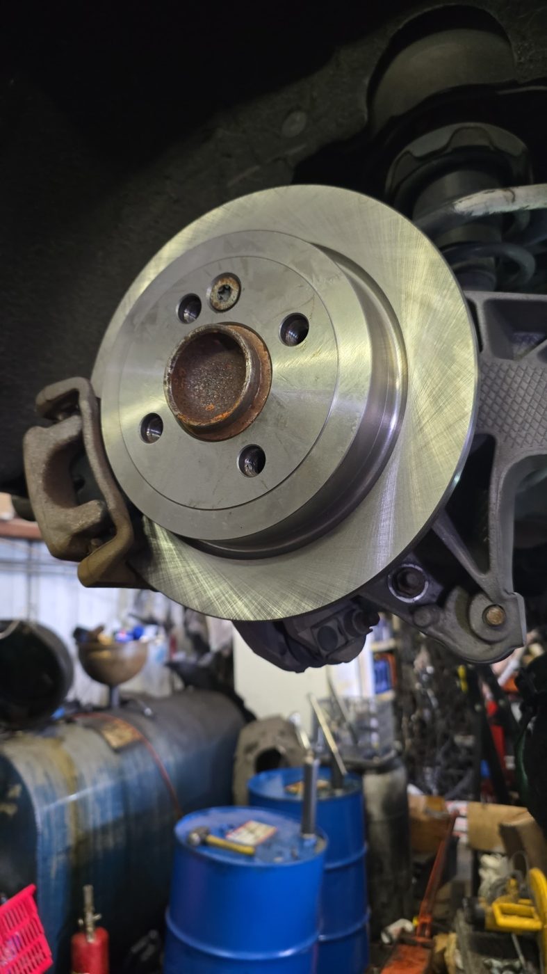 Brake rotor and caliper exposed with the wheel off at Front Line Auto in Oakland Park