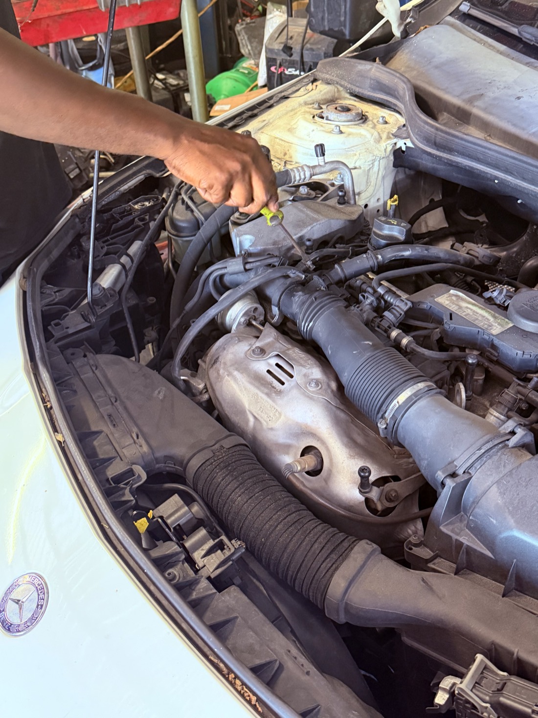 Technician checking under the hood of a Mercedes-Benz at Front Line Auto in Oakland Park