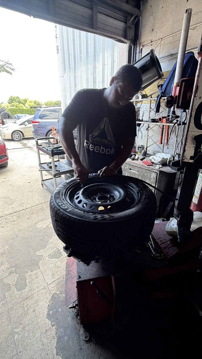 Technician working a wheel on the tire machine at Front Line Auto in Oakland Park