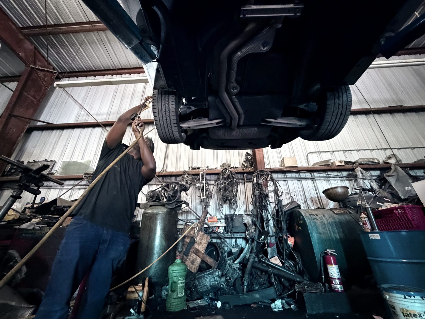 View from beneath a raised vehicle while a Front Line Auto technician works on the underbody in Oakland Park