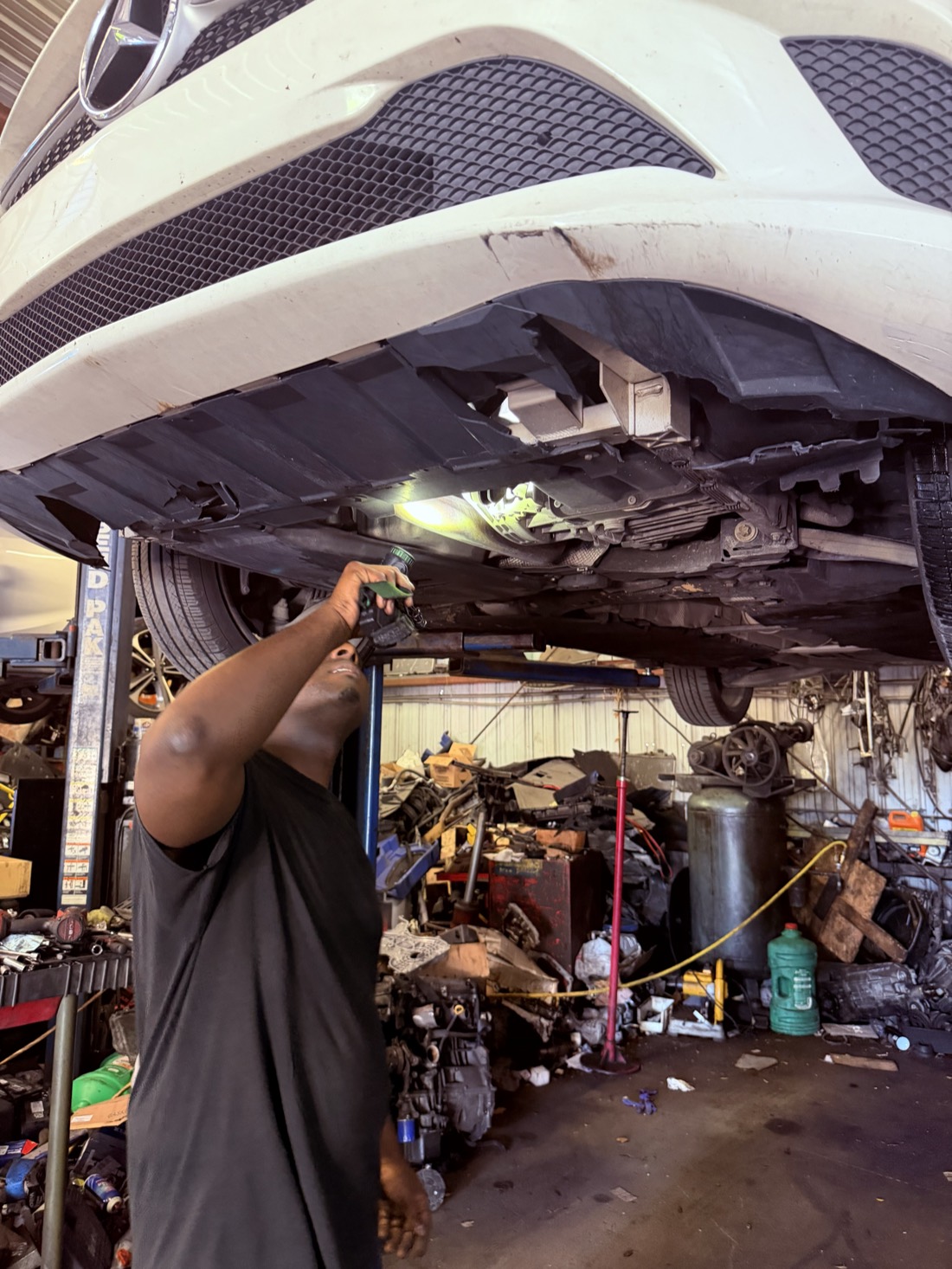 Technician using a light during underbody inspection at Front Line Auto