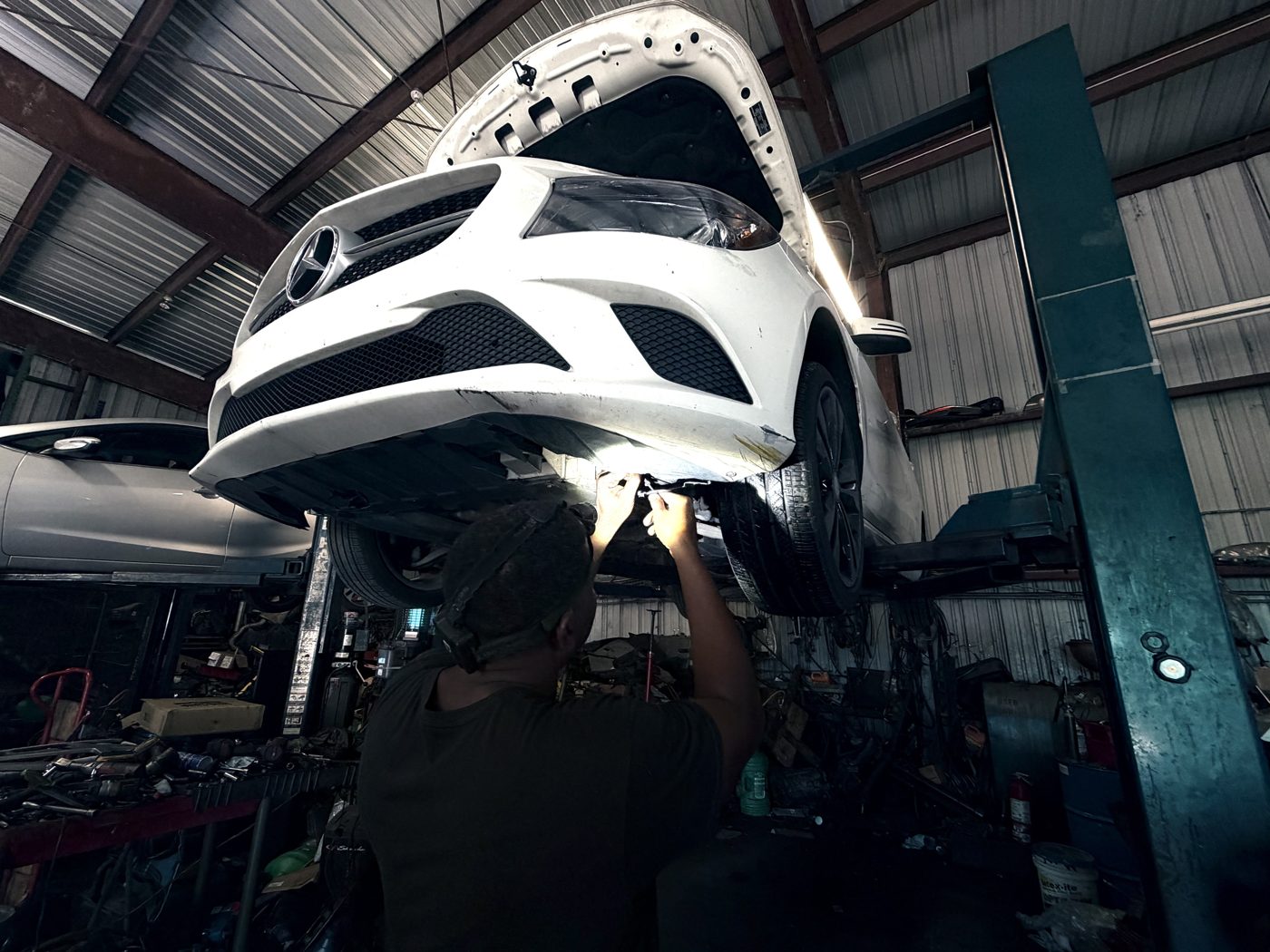 Vehicle raised on a two-post lift with a technician working underneath at Front Line Auto