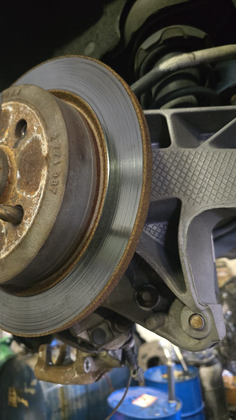 Worn brake rotor showing a lip and surface rust during inspection at Front Line Auto
